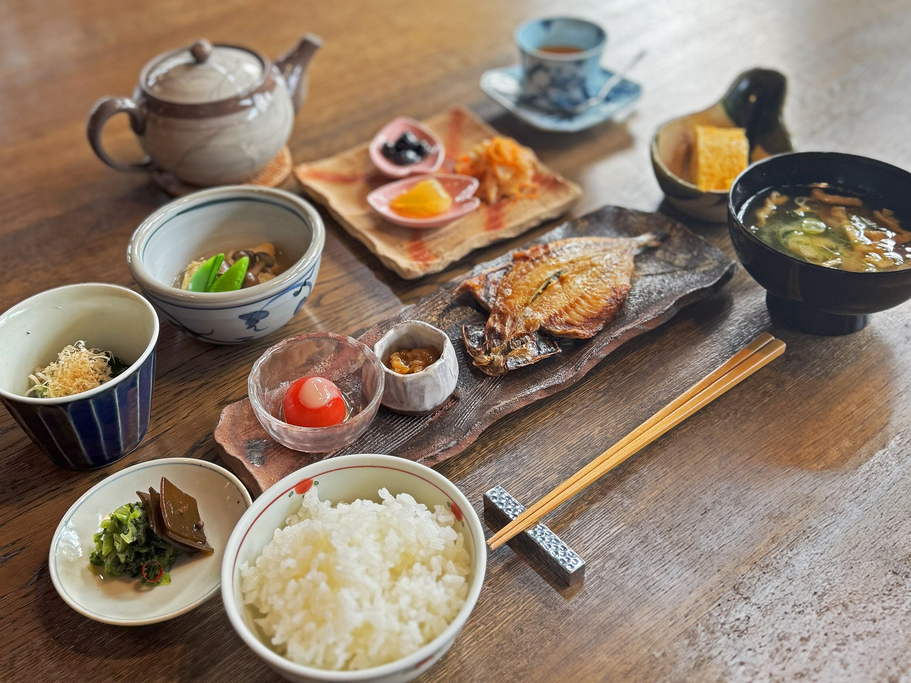 A traditional Japanese meal with various dishes including rice, fish, and soup, served on a wooden table.