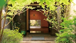 A traditional Japanese-style entrance with a wooden door and a small window, surrounded by lush greenery. - Yufuin Onsen Ryokan Hananomai (Yufu)