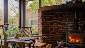A cozy room with a stone fireplace, wooden furniture, and a view of greenery outside. - Yufuin Onsen Ryokan Hananomai (Yufu)