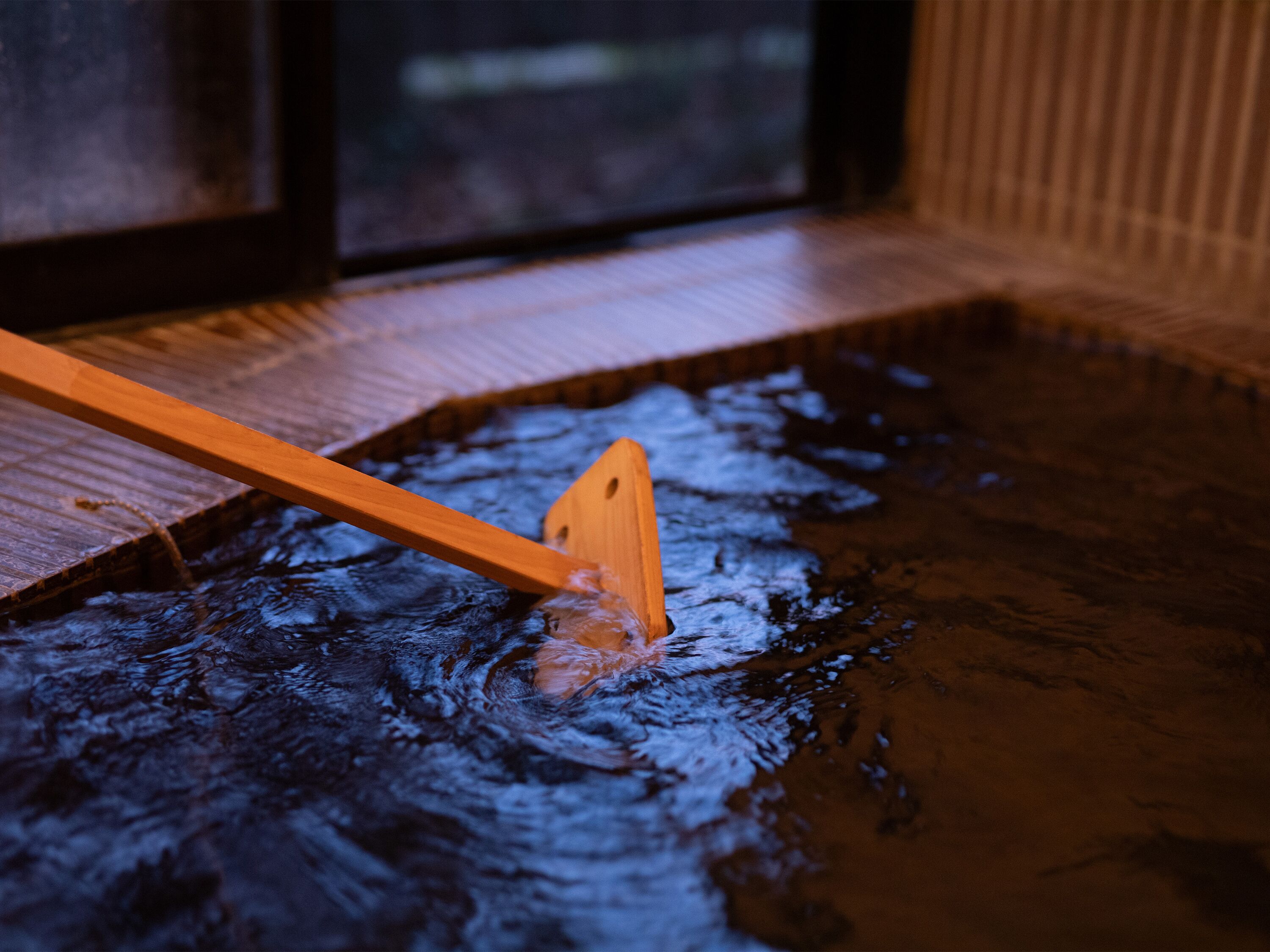 Una cuchara de madera en un pequeño charco de agua, probablemente parte de un área de spa o relajación.