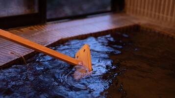A wooden spoon in a shallow pool of water, likely part of a spa or relaxation area.