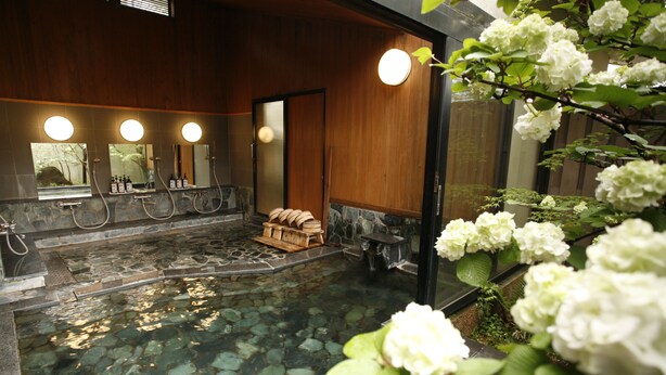 A spa area with a stone pool, wooden benches, and a wooden wall with mirrors. - Yufuin Onsen Ryokan Hananomai (Yufu)
