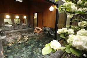 A spa area with a stone pool, wooden benches, and a wooden wall with mirrors. - Yufuin Onsen Ryokan Hananomai (Yufu)
