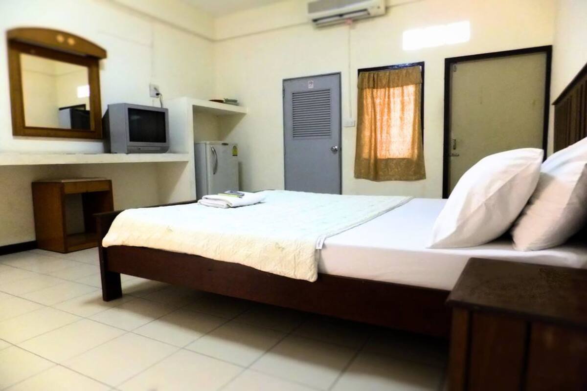 A bedroom with a bed, a television, a wardrobe, and a mirror.