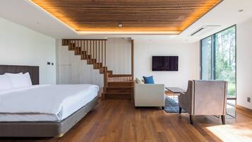 A modern bedroom with a large bed, a desk, a chair, and a staircase.