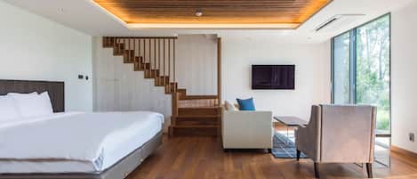 A modern bedroom with a large bed, a desk, a chair, and a staircase.