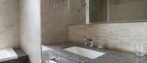 A modern bathroom with a shower, two sinks, a mirror, and a glass shower enclosure.