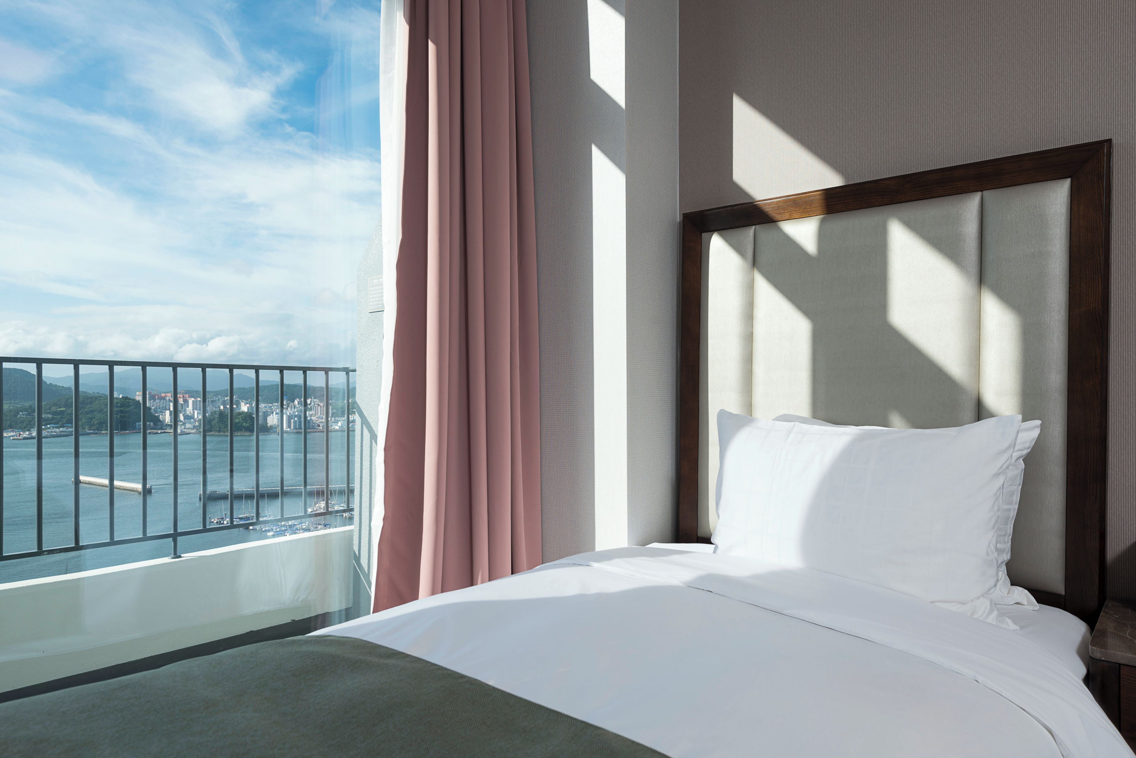 A hotel room with a bed, a view of the sea, and a balcony.