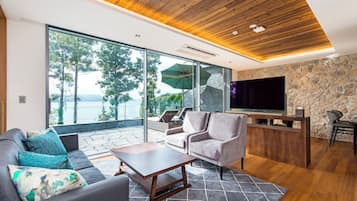 Een moderne woonkamer met een bank, salontafel en een televisie. Er is een stenen muur en een houten plafond.