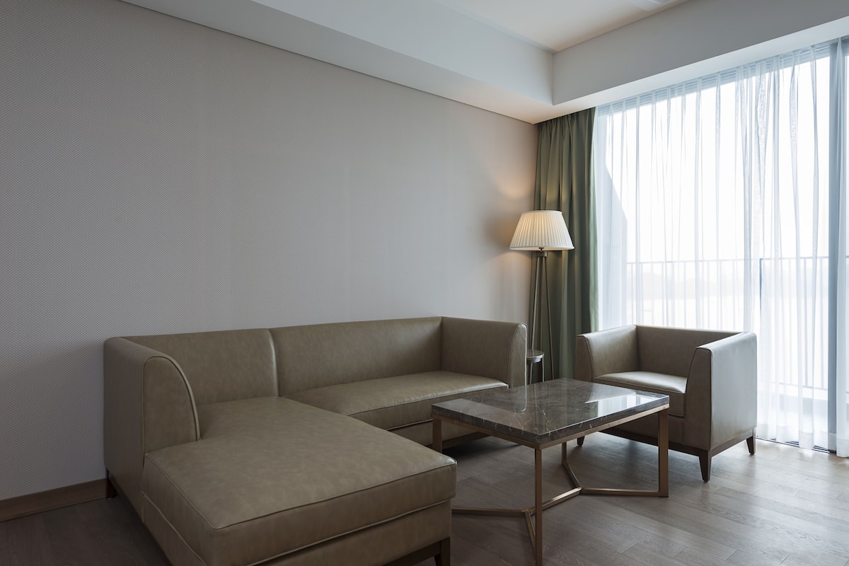 Habitació d'hotel moderna amb un sofà modular, una taula petita i una làmpada.
