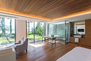 Un dormitorio moderno con una cama grande, un escritorio y una silla. Cuenta con un box de ducha de vidrio y vistas al exterior.