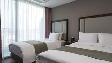 A hotel room with two beds, a large window with sheer curtains, and a modern air conditioning unit.