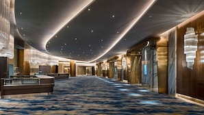 A spacious hotel corridor with a blue carpet, modern chandeliers, and a sleek, contemporary design. - PRIMUS Hotel Shanghai Hongqiao (Shanghai)