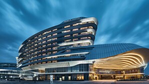 A modern hotel with a curved facade, multiple balconies, and a distinctive entrance. - PRIMUS Hotel Shanghai Hongqiao (Shanghai)