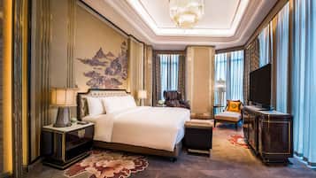 A luxurious hotel room with a large bed, a massage chair, a television, and a decorative wall piece.