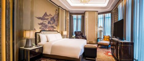 Een luxe hotelkamer met een groot bed, een massagestoel, een televisie en een decoratief wandobject.