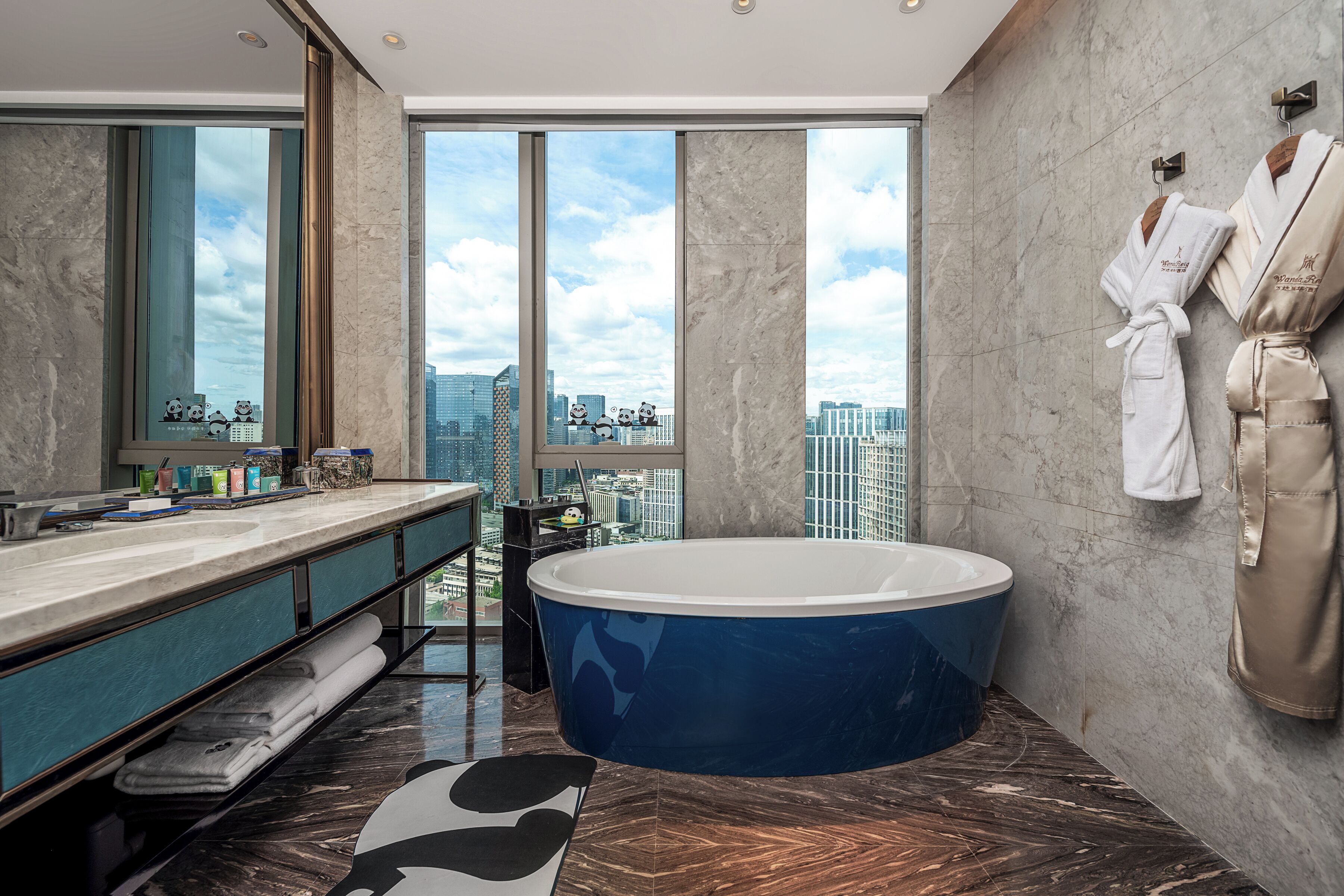 A modern bathroom with a large bathtub, a vanity with a mirror, and a view of a cityscape through large windows.
