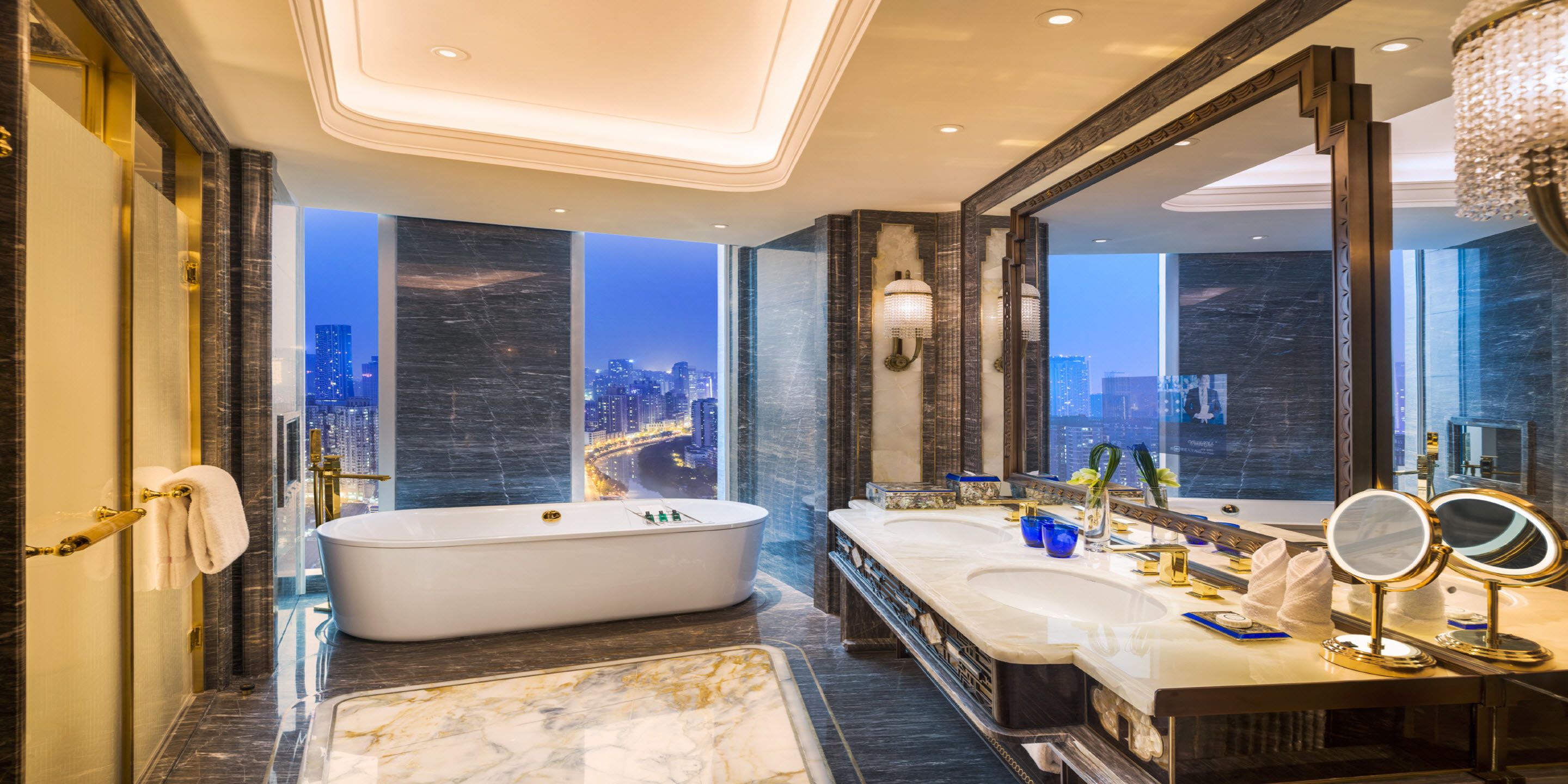 Un baño lujoso con una bañera grande, lavamanos dobles y vistas a la ciudad.
