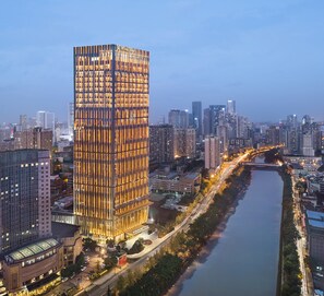 A high-rise building with a modern design, surrounded by a river and other urban structures.