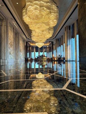 A spacious hotel lobby with a large chandelier, marble floors, and large windows allowing natural light. - Wanda Reign Chengdu (Chengdu)
