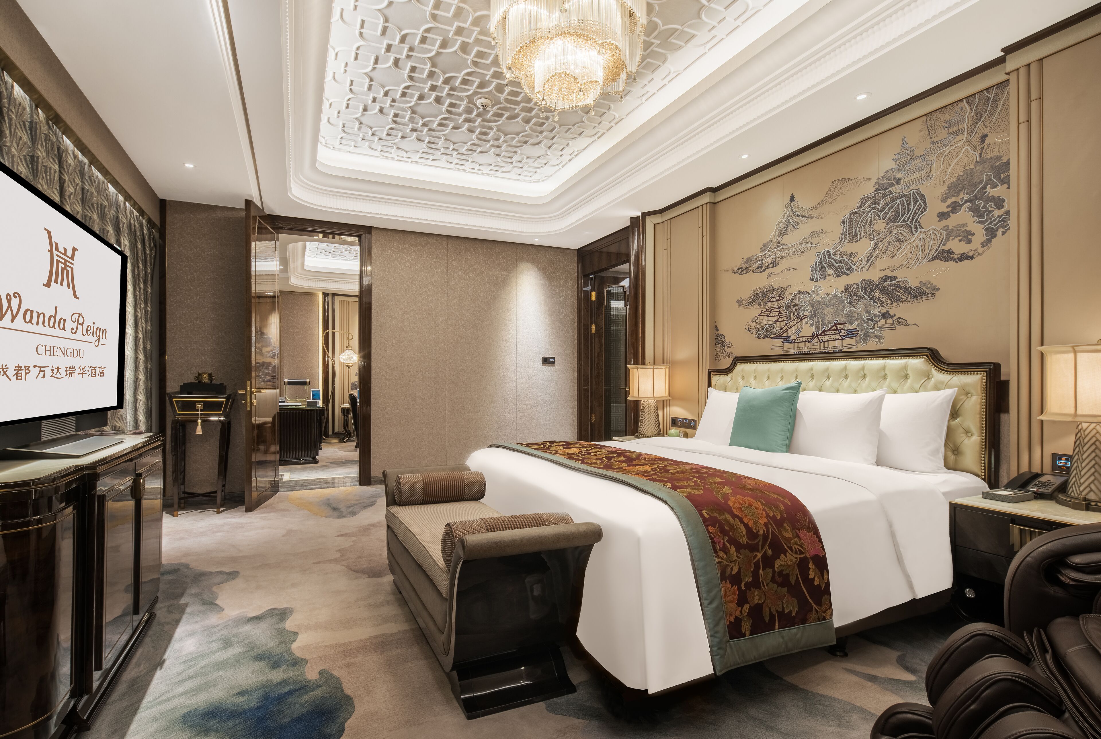 A spacious hotel room with a large bed, a television, a desk, and a decorative wall.