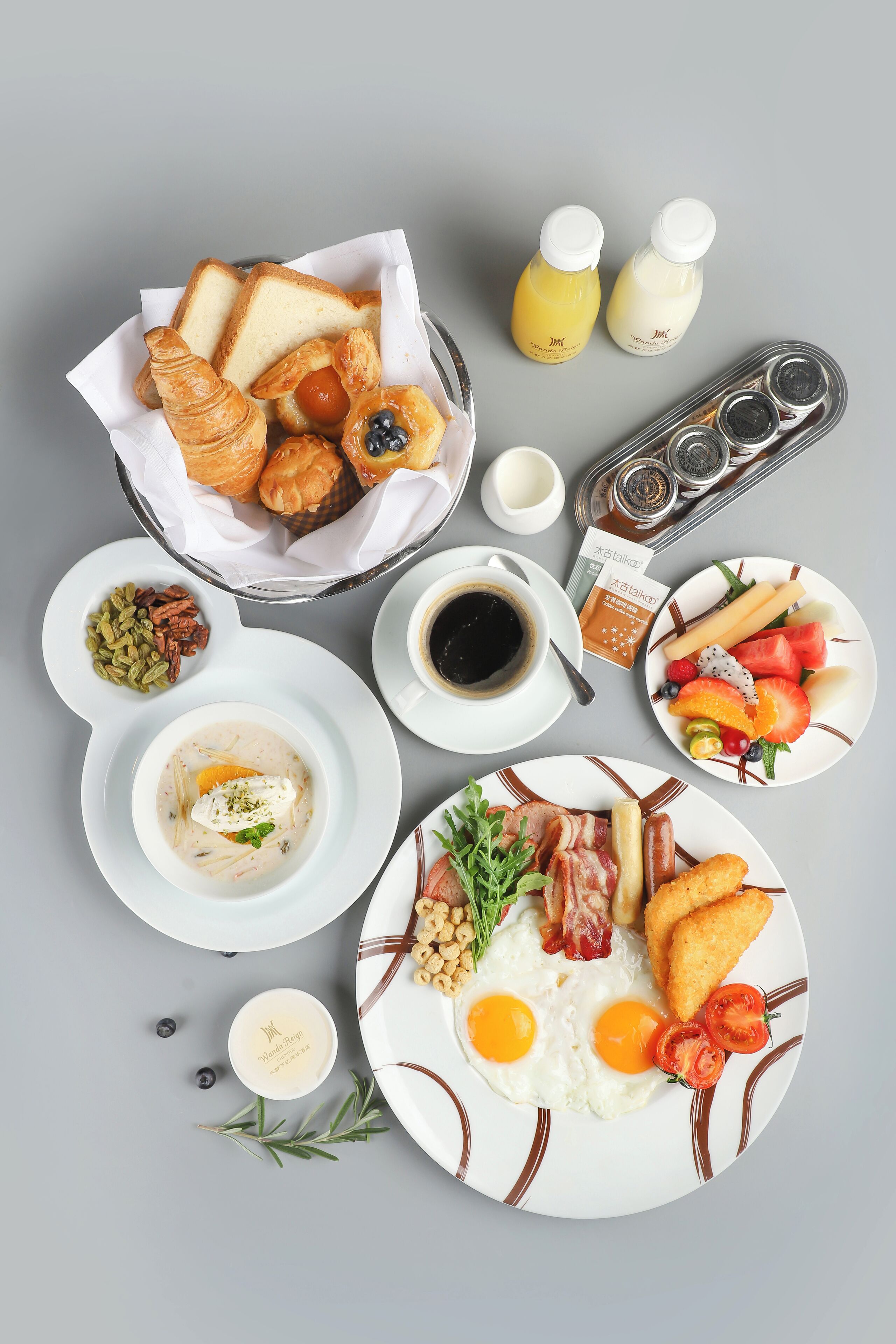 A breakfast spread with croissants, eggs, bacon, and various fruits and pastries.