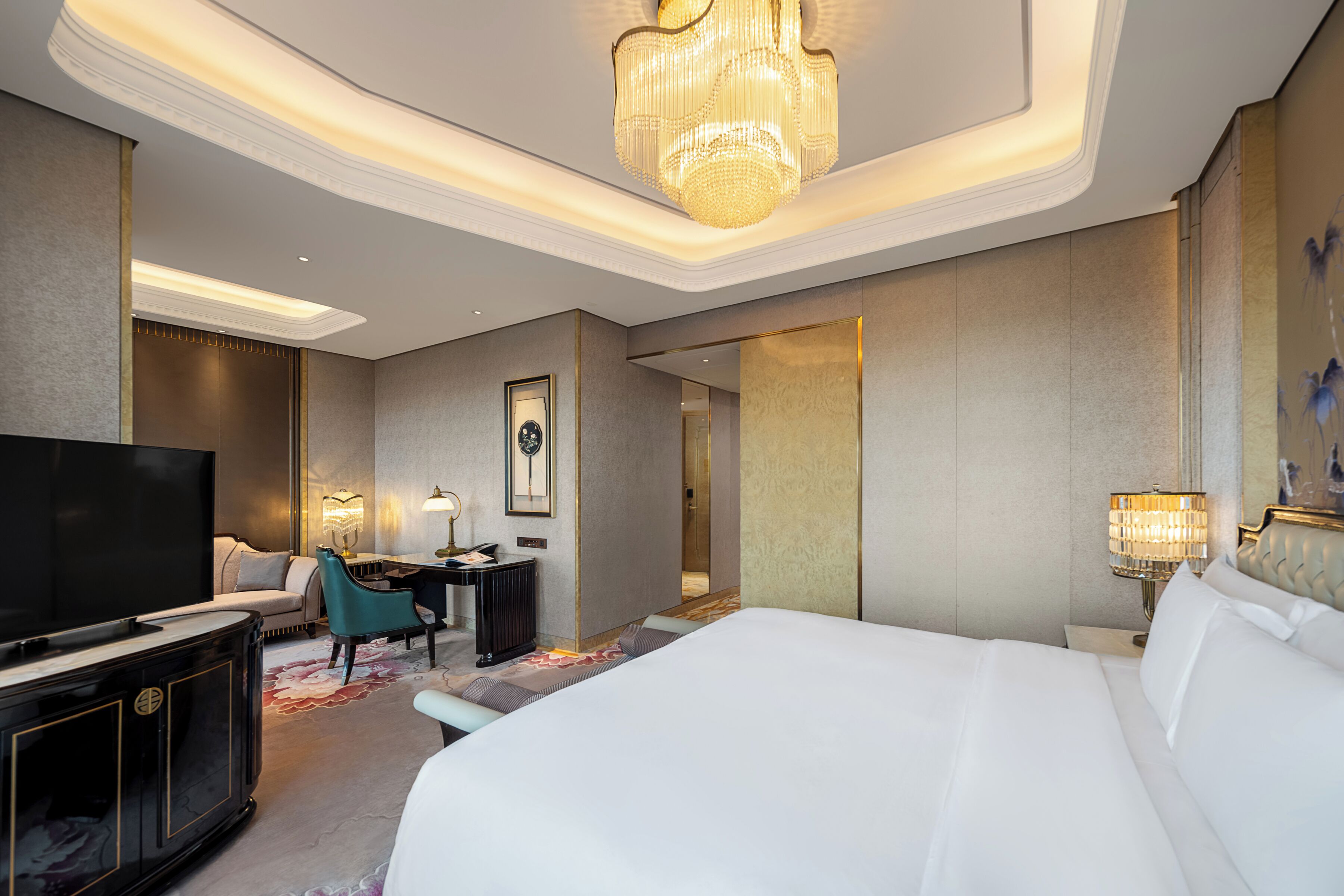 Una habitación de hotel con una cama grande, televisión, escritorio y candelabro.