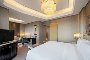 Una habitación de hotel con una cama grande, televisión, escritorio y candelabro.