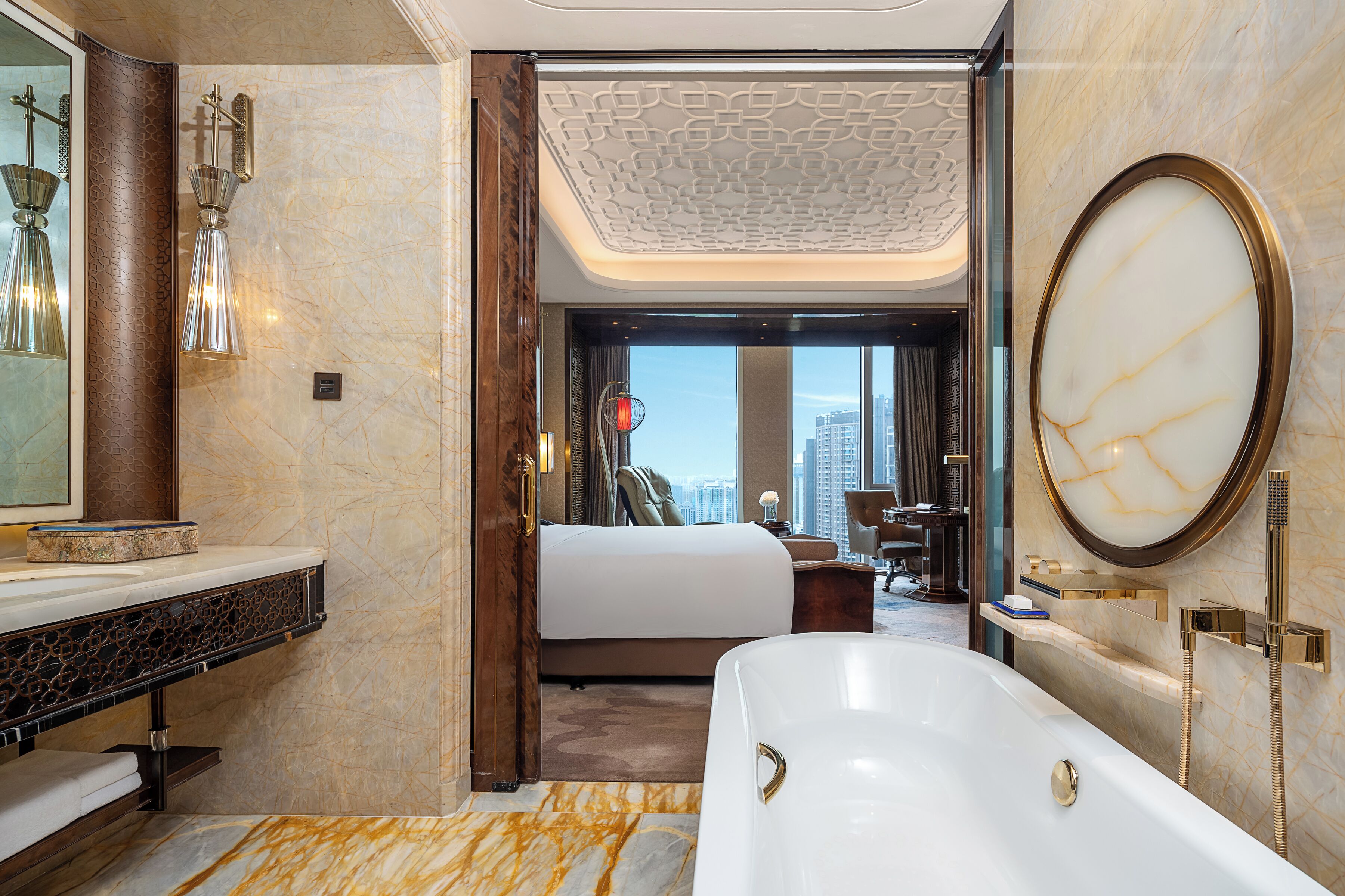 Ein Hotelzimmer mit einer großen Badewanne, einem Bett, einem Schminktisch und Blick auf die Stadt.