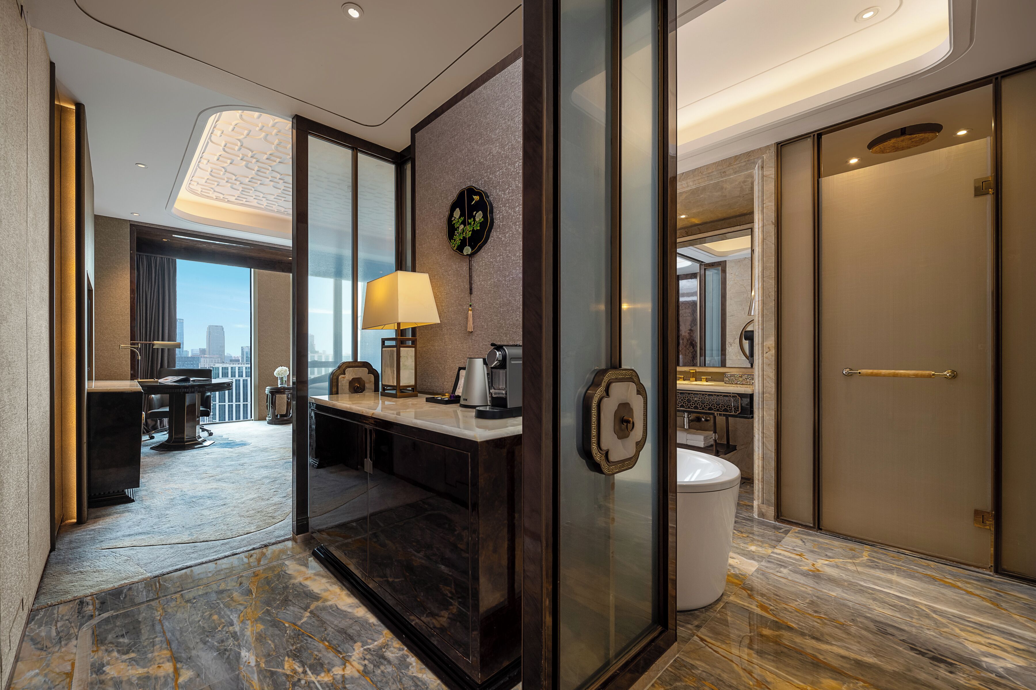 Een hotel lobby met een marmeren vloer, een receptiebalie, een wandklok en uitzicht op de stadsgezicht.
