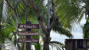 Un cartel con indicaciones hacia 'Lél Rustique Bar', 'Samui Caravans' y 'Camping Farm'.