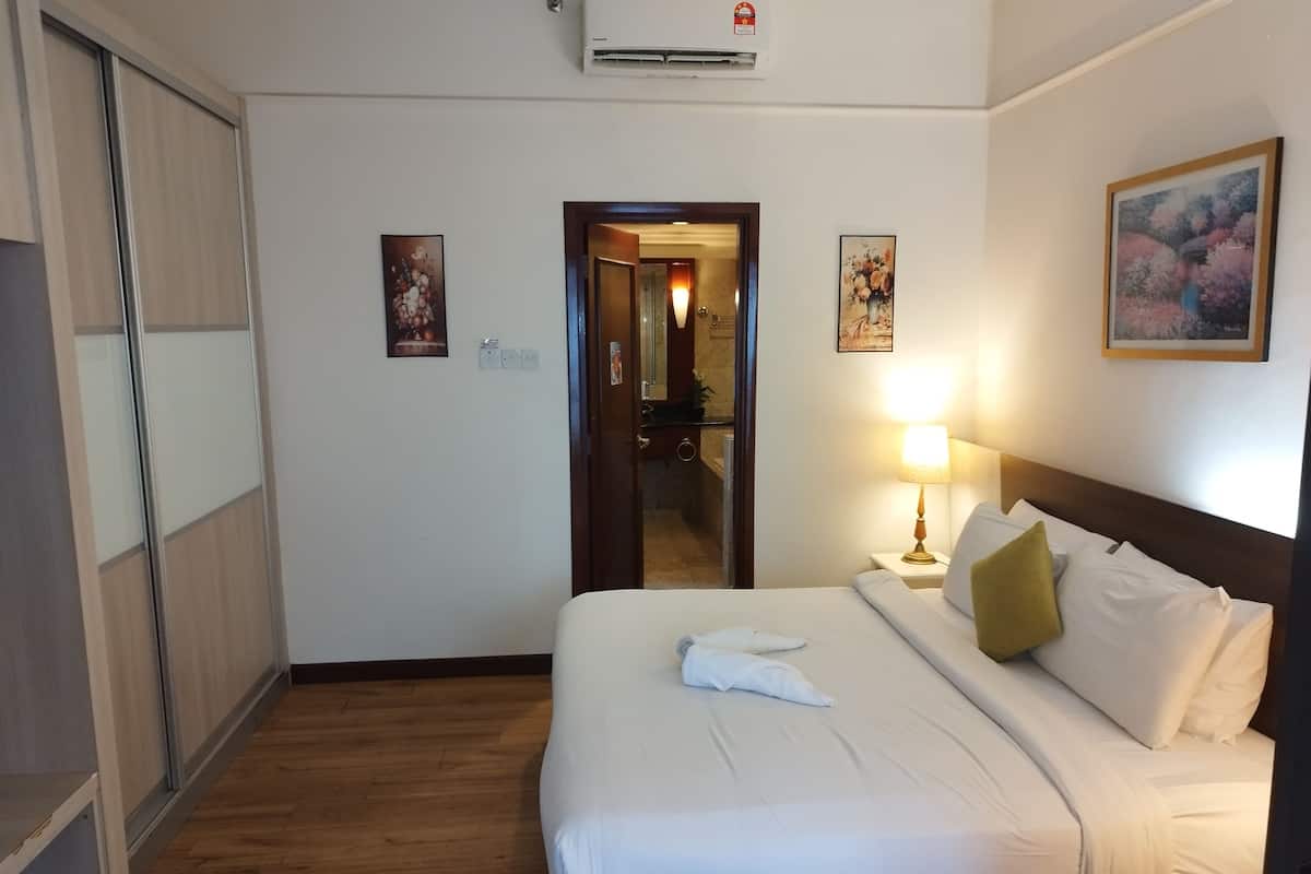 A hotel room with a bed, bedside lamp, and a painting on the wall.