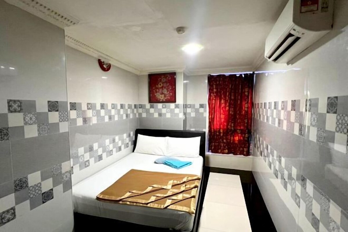 Ein Hotelzimmer mit einem Bett, einem roten Vorhang, einer Wand-Klimaanlage und gemusterten Fliesen.