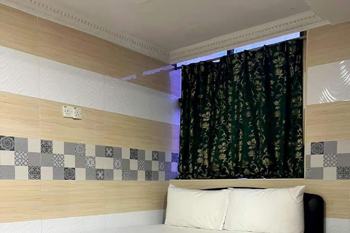 Une chambre d’hôtel moderne avec un grand lit, une table de chevet et une fenêtre agrémentée de rideaux à motifs.