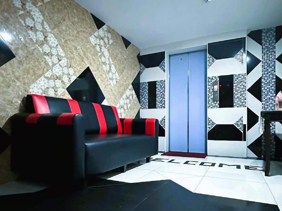 A modern living room with a black and red sofa, a patterned wall, and a tiled floor.