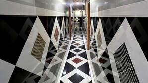 A hallway with a geometric patterned floor, white walls, and a decorative ceiling. - Sungai Besi Hotel (Seri Kembangan)