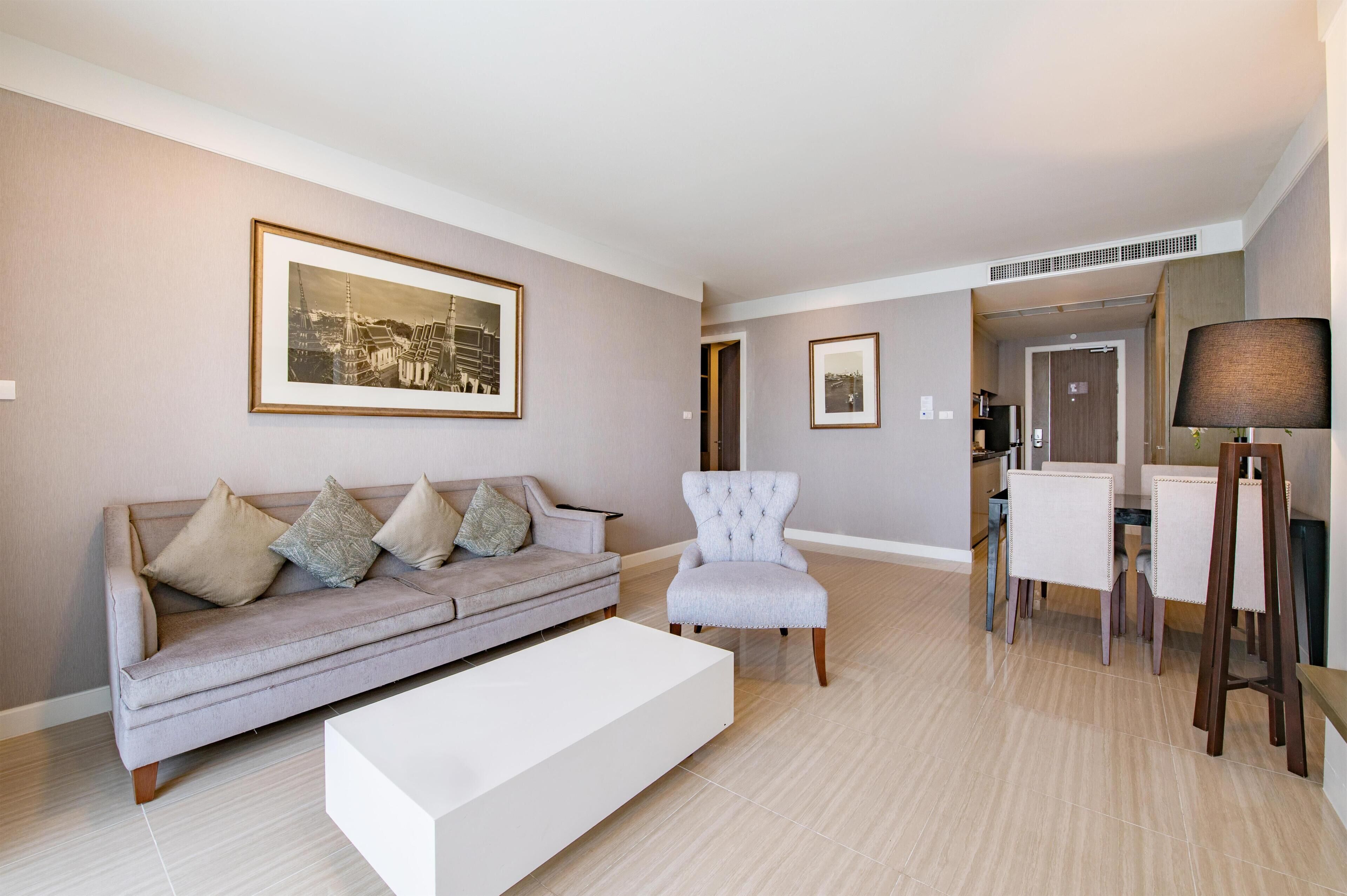 Una sala de estar con sofá, sillón, mesa de comedor y sillas.