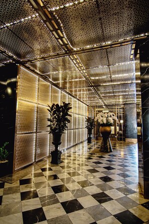 A lobby with a checkered floor, patterned walls, and decorative lighting. - Metropolis Suites Bangkok, Tapestry Collection by Hilton (Bangkok)