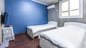 Una habitación con dos camas, televisión y aire acondicionado.