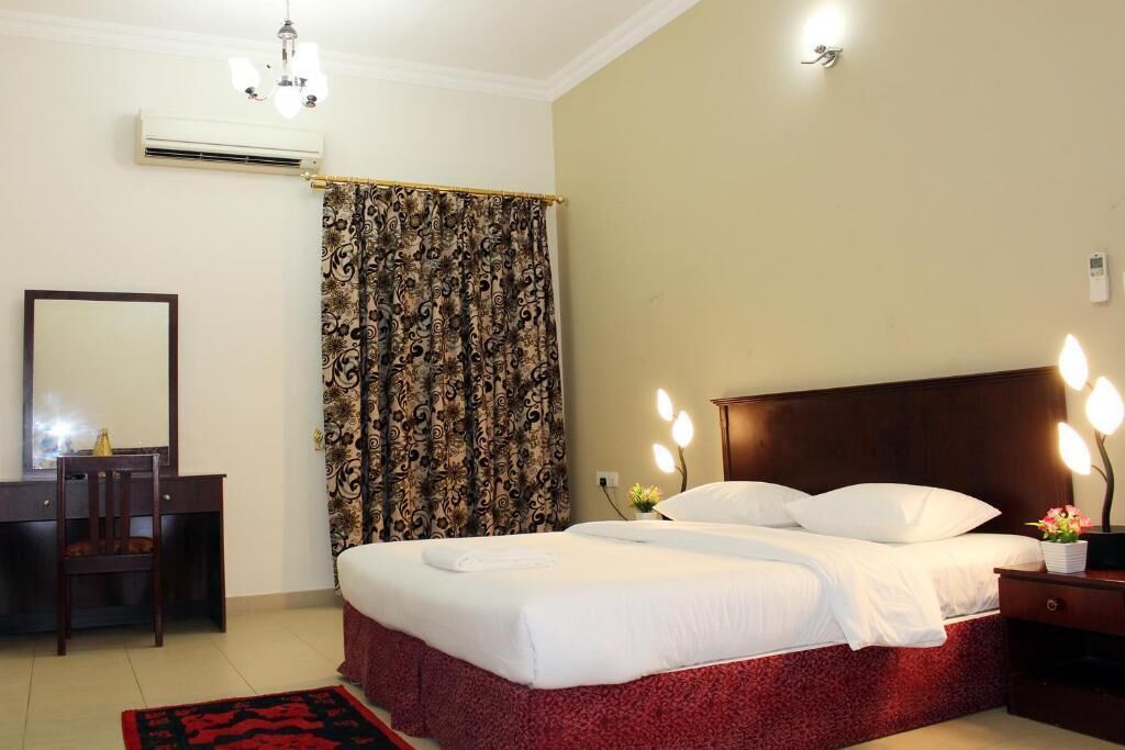 Une chambre d’hôtel équipée d’un lit, d’un bureau, d’une chaise, d’un climatiseur et de rideaux.