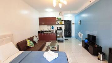 A compact living space with a bed, a sofa, a kitchenette, and a dining area.