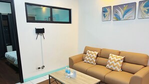 A modern living room with a sofa, pillows, a coffee table, and a wall-mounted TV. - Serena's House - Manila (Manila)