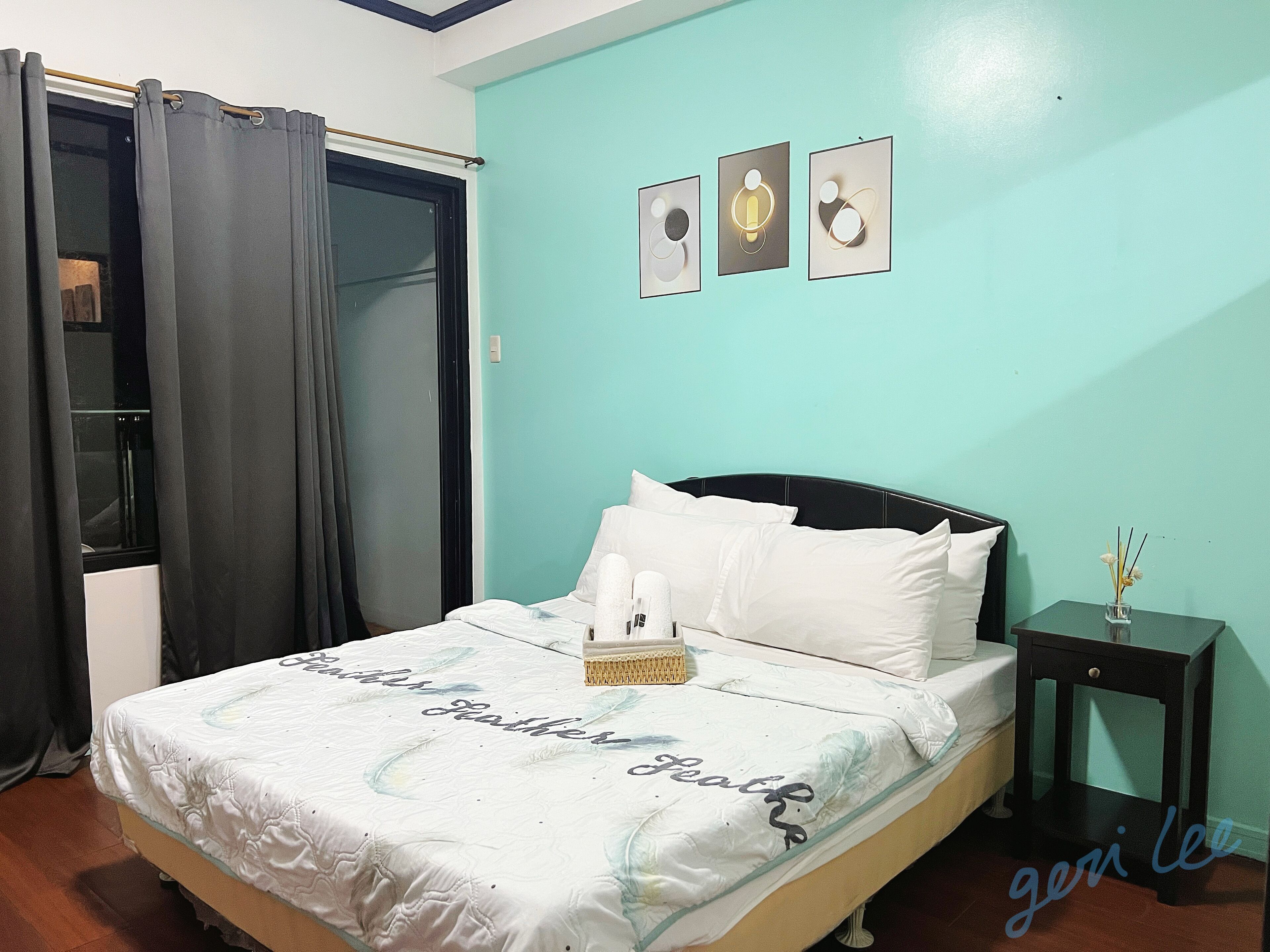 A bedroom with a bed, a bedside table, a nightstand, and a window with curtains.