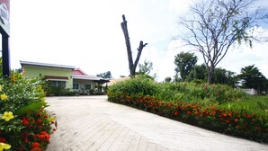 A paved pathway leading to a building with a red roof, surrounded by vibrant red and yellow flowers. - Sweethome Resort (Surin)