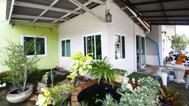 A covered outdoor area with a garden, a small pond, and a seating area with a table and chairs. - Sweethome Resort (Surin)
