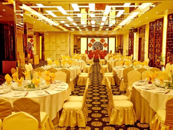A banquet hall with round tables, yellow chairs, and floral centerpieces.