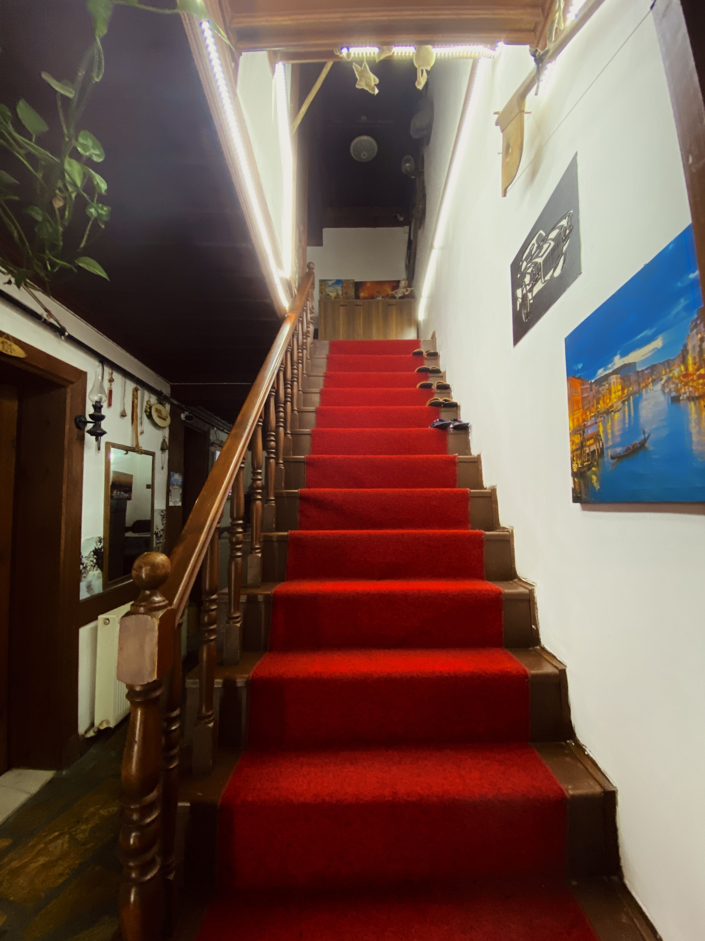 Eine Treppe mit rotem Teppich, Holzhandläufen und einer Wand mit einem gerahmten Gemälde.