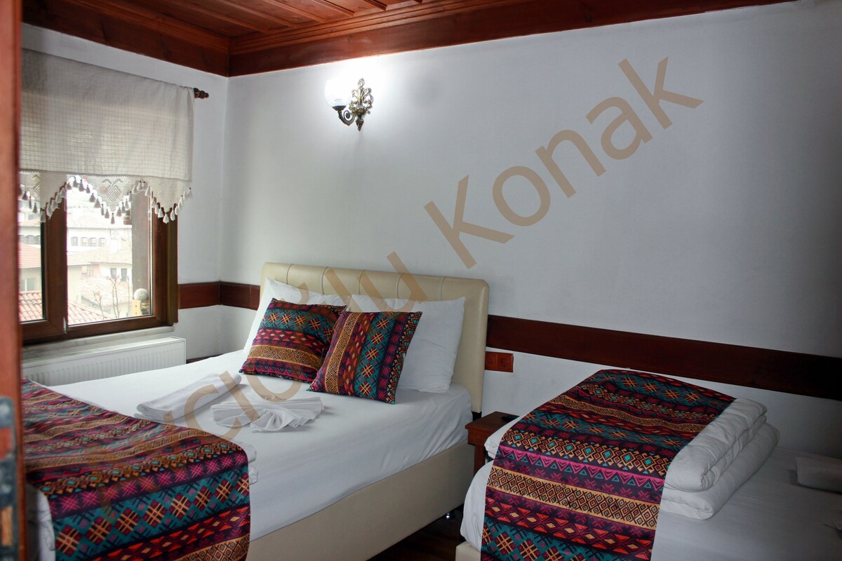 Habitación de hotel con dos camas, una ventana con cortinas, una lámpara de pared y un radiador.