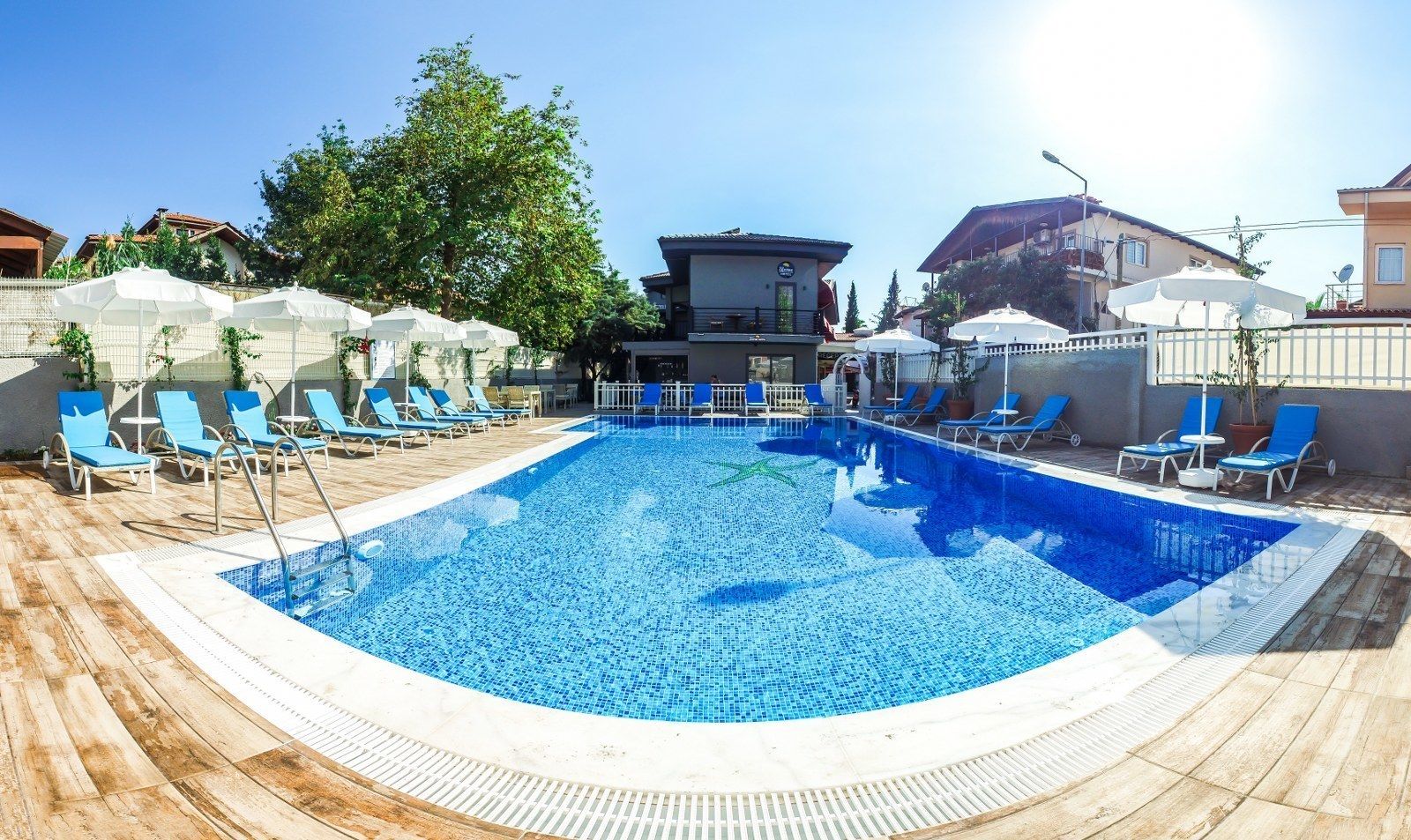 A rectangular swimming pool with a tiled edge, surrounded by lounge chairs and umbrellas.