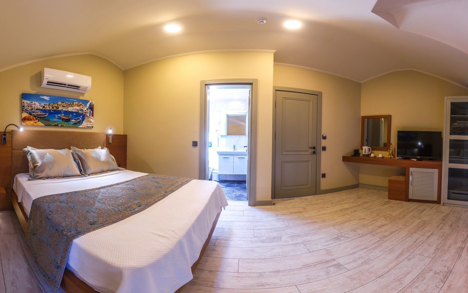 A bedroom with a bed, a TV, a desk, and a wardrobe.
